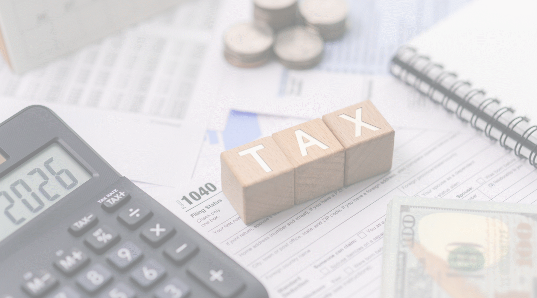 Calculator, wooden blocks spelling TAX, money, and documents on a desk for financial tax preparation.
