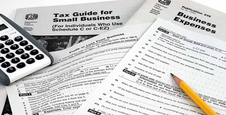 Business tax return Tax documents, a calculator, and a pencil arranged for small business tax and CFO-focused expense forms.